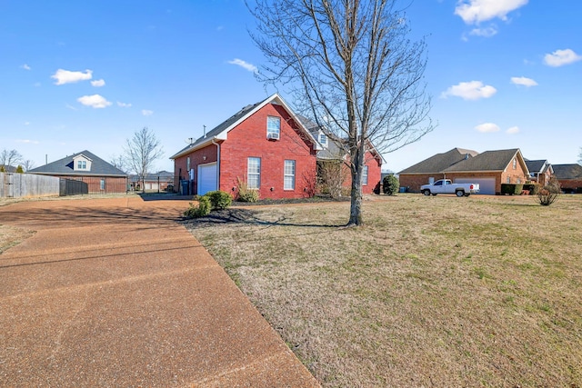 exterior space featuring driveway, an attached garage, fence, a front lawn, and brick siding