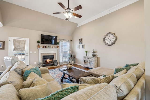 living room with baseboards, ceiling fan, a fireplace with flush hearth, wood finished floors, and vaulted ceiling