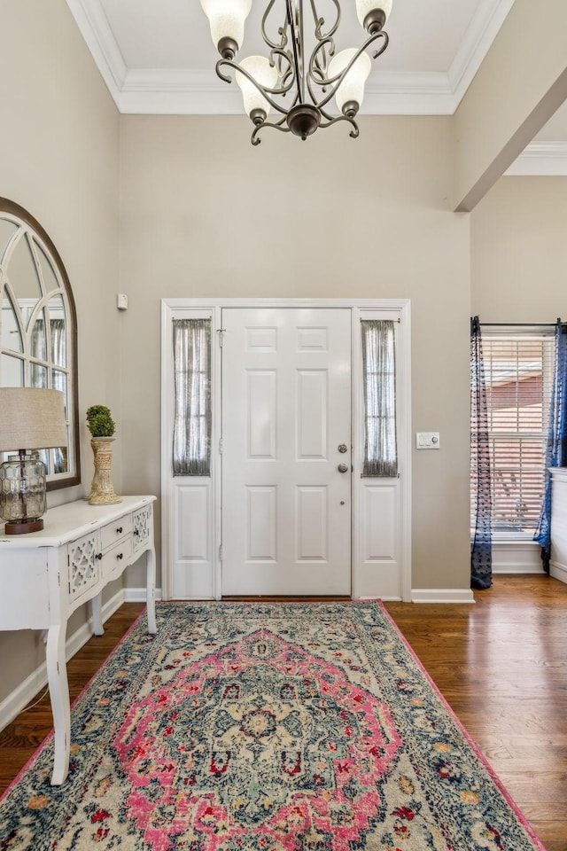 entrance foyer featuring baseboards, ornamental molding, a chandelier, and wood finished floors