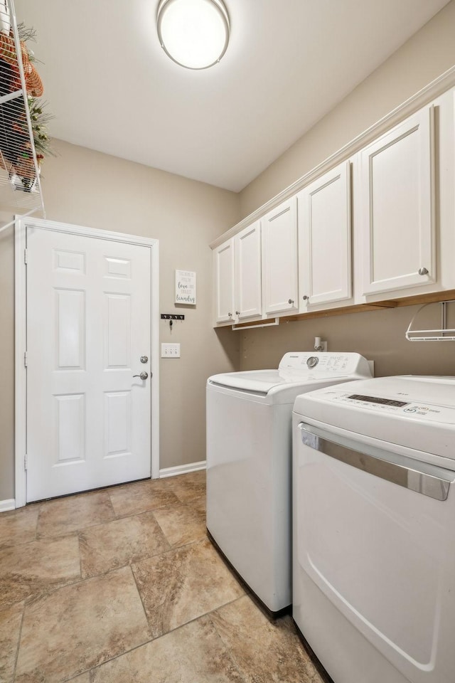 laundry room with cabinet space, stone finish flooring, baseboards, and independent washer and dryer