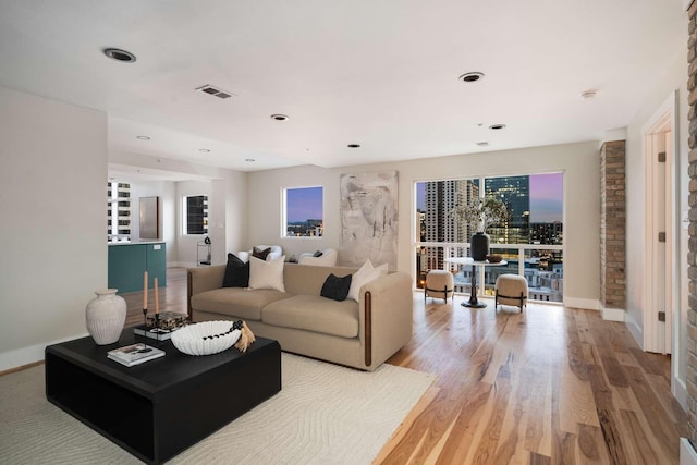 living room featuring baseboards, visible vents, wood finished floors, and recessed lighting