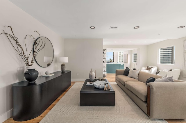 living room featuring light wood finished floors, baseboards, visible vents, and recessed lighting