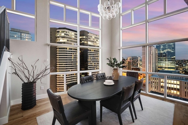 dining area featuring a notable chandelier, a city view, wood finished floors, baseboards, and floor to ceiling windows