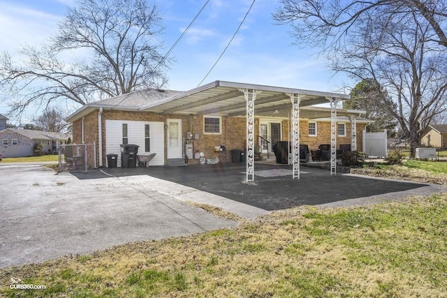 rear view of house with driveway, brick siding, fence, and an attached carport