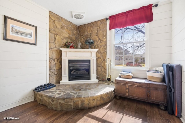 living area featuring dark wood-type flooring, a glass covered fireplace, and visible vents