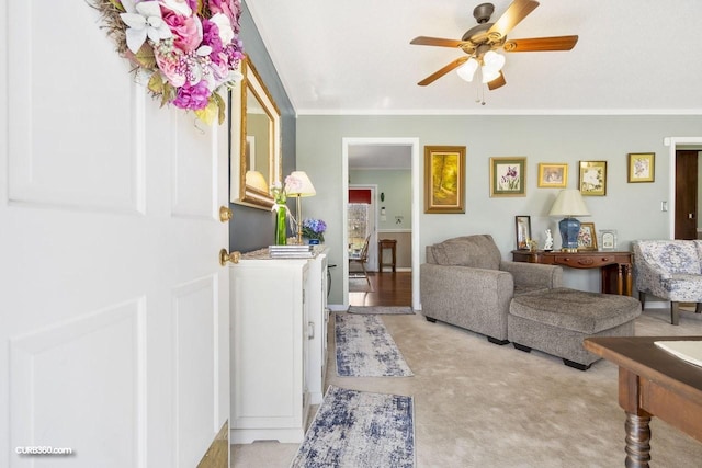 living area featuring light carpet, crown molding, and a ceiling fan