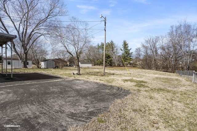 view of yard with a shed, fence, and an outbuilding