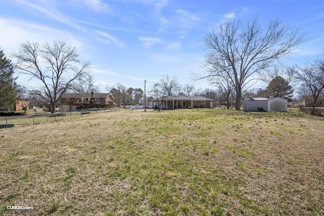 view of yard with a storage shed, fence, and an outbuilding