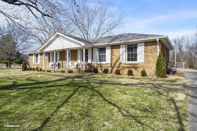 view of front of house with a front yard, a porch, and brick siding