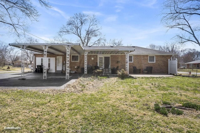 back of house featuring an attached carport, brick siding, and a lawn