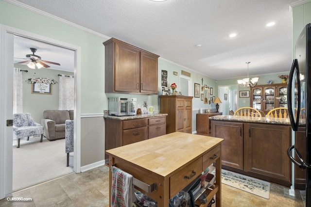 kitchen featuring crown molding, hanging light fixtures, freestanding refrigerator, a textured ceiling, and wood counters