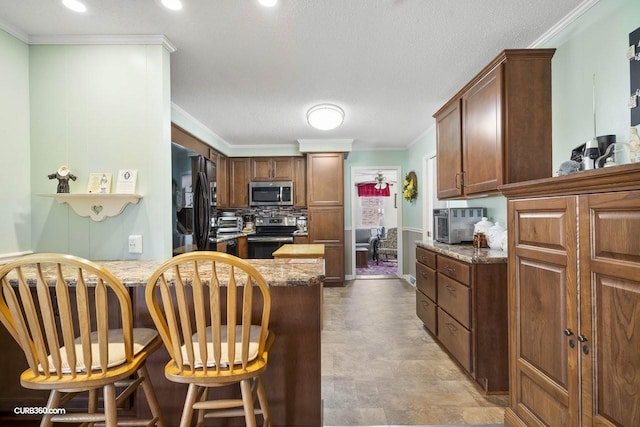 kitchen featuring stone counters, stainless steel appliances, backsplash, ornamental molding, and a peninsula