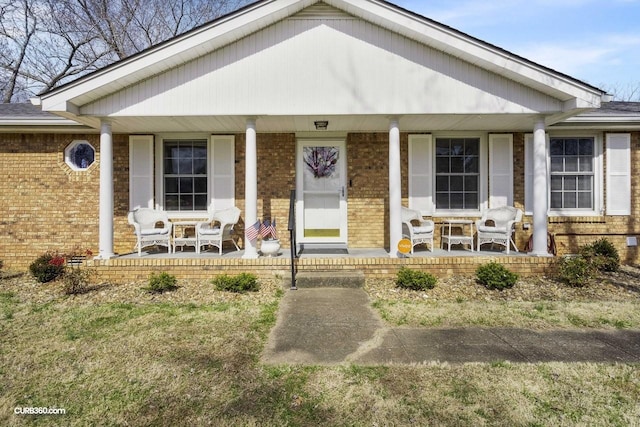 property entrance with covered porch and brick siding