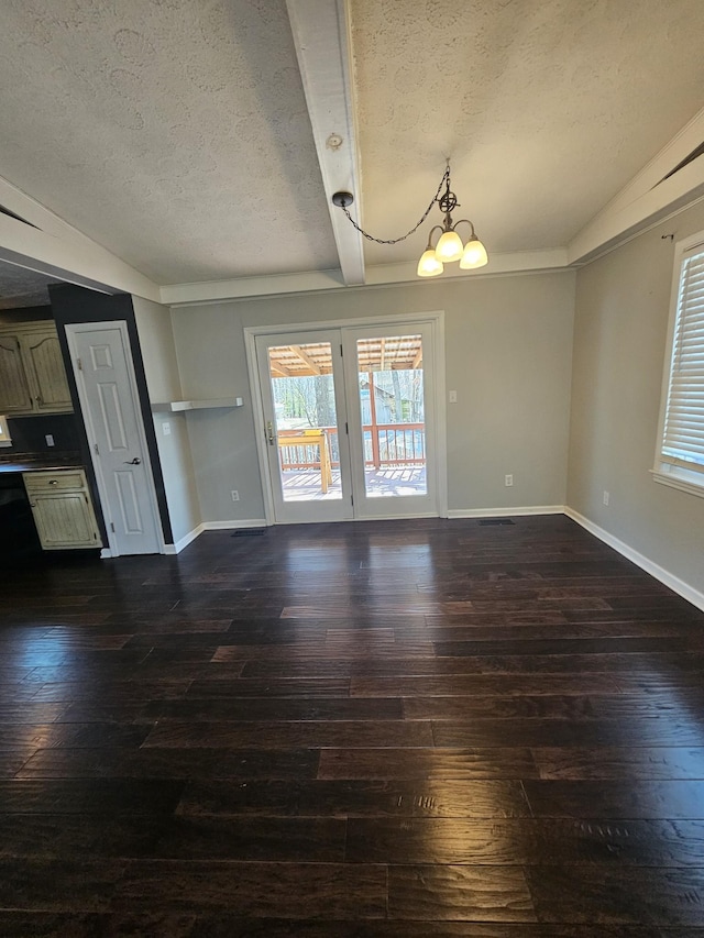 unfurnished dining area with dark wood-type flooring, a chandelier, plenty of natural light, and a textured ceiling