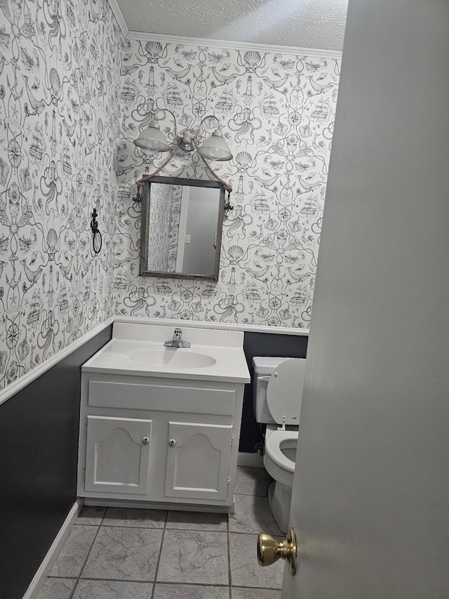 bathroom with a textured ceiling, toilet, vanity, and wallpapered walls