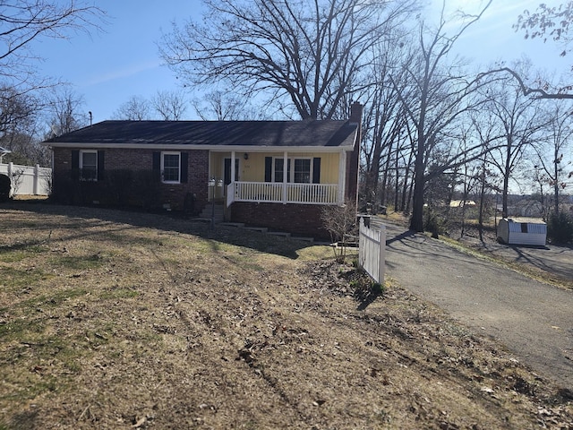 view of front of home with covered porch, a chimney, and brick siding