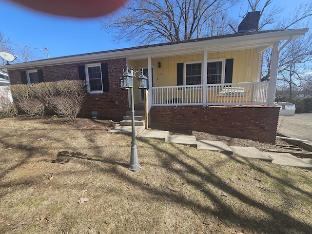 view of front of home with crawl space, a chimney, a porch, and brick siding