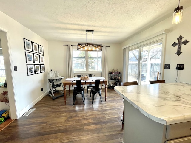 dining room featuring baseboards, a textured ceiling, visible vents, and dark wood-type flooring