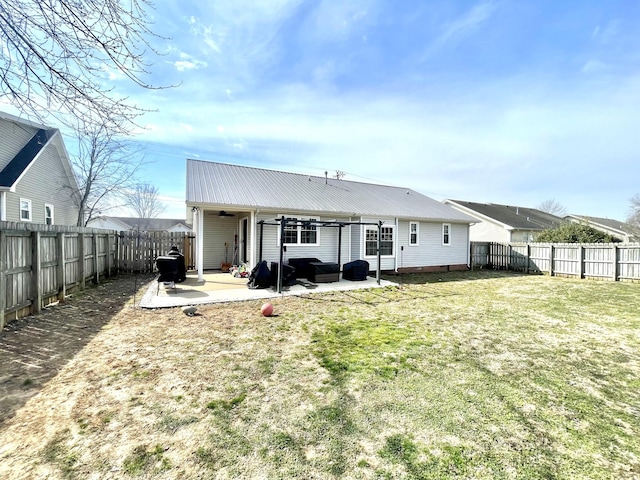 rear view of house featuring a fenced backyard, metal roof, a lawn, and a patio