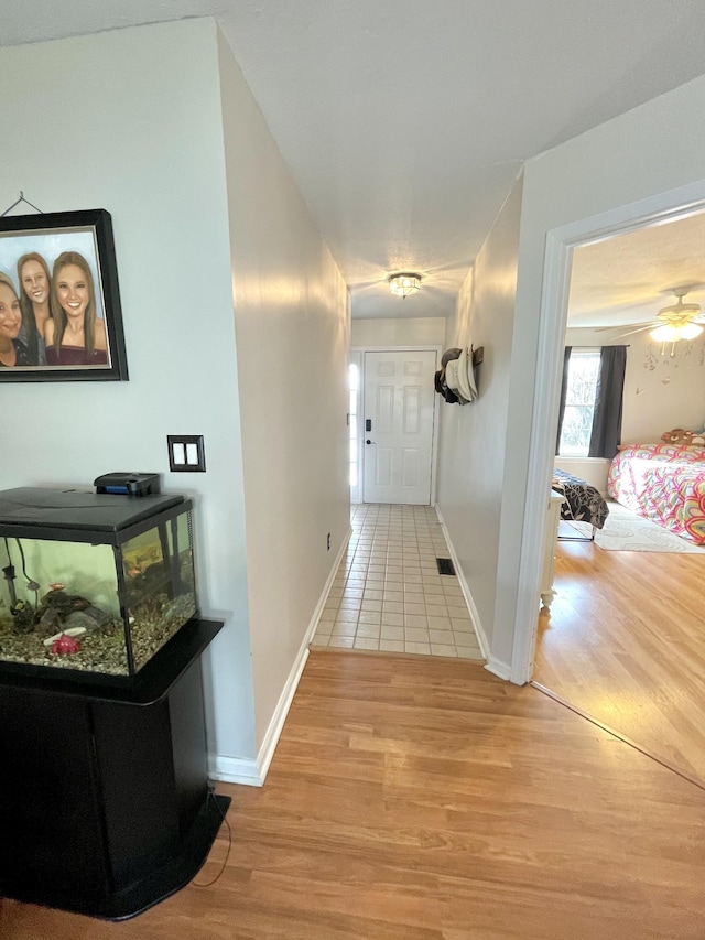 corridor with visible vents, light wood-style flooring, and baseboards