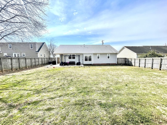 rear view of property featuring a fenced backyard, metal roof, a lawn, and a patio