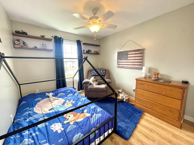 bedroom featuring a ceiling fan, baseboards, and wood finished floors