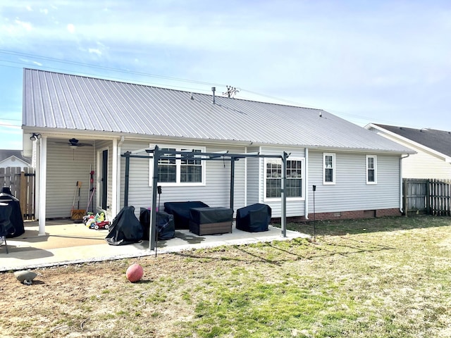 rear view of house with metal roof, a patio, a lawn, and fence