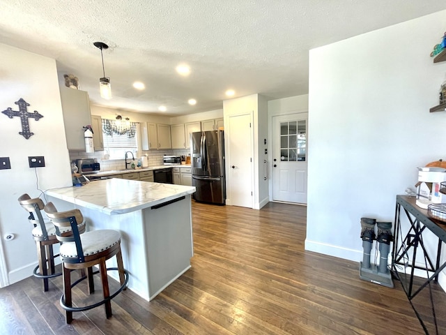 kitchen with stainless steel fridge, decorative backsplash, dark wood-style floors, a peninsula, and light countertops