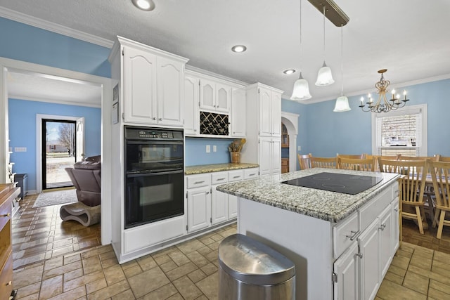 kitchen with a healthy amount of sunlight, black appliances, white cabinets, and a center island