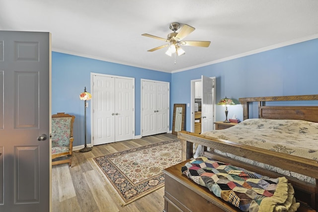 bedroom with crown molding, multiple closets, a ceiling fan, wood finished floors, and baseboards