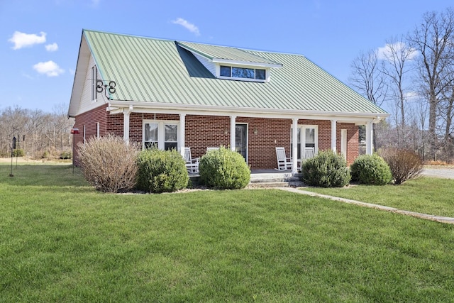 view of front of home with a porch, a front yard, metal roof, and brick siding