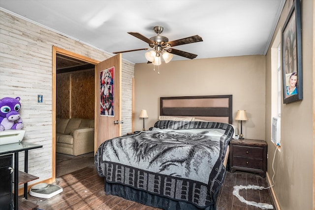 bedroom with ceiling fan, wooden walls, and wood finished floors