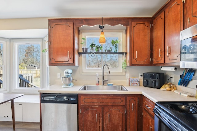 kitchen with stainless steel appliances, a wealth of natural light, light countertops, and a sink