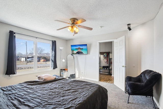 bedroom with a ceiling fan, a textured ceiling, and baseboards