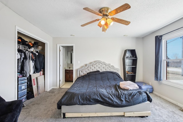 carpeted bedroom with baseboards, a ceiling fan, connected bathroom, a textured ceiling, and a closet