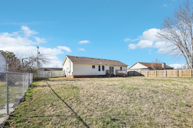 rear view of property with a fenced backyard, a wooden deck, and a yard