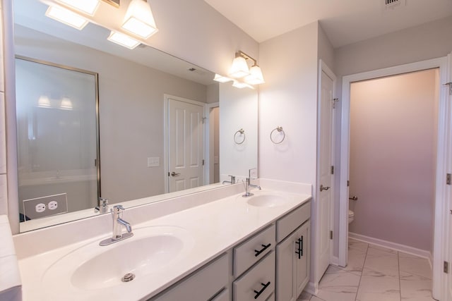 bathroom featuring marble finish floor, double vanity, a sink, and baseboards