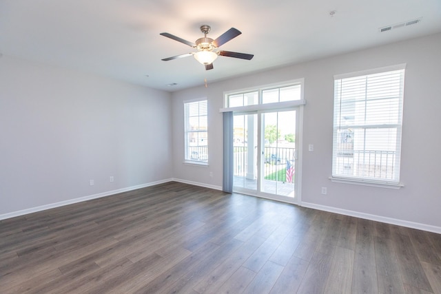 empty room featuring ceiling fan, baseboards, visible vents, and dark wood finished floors