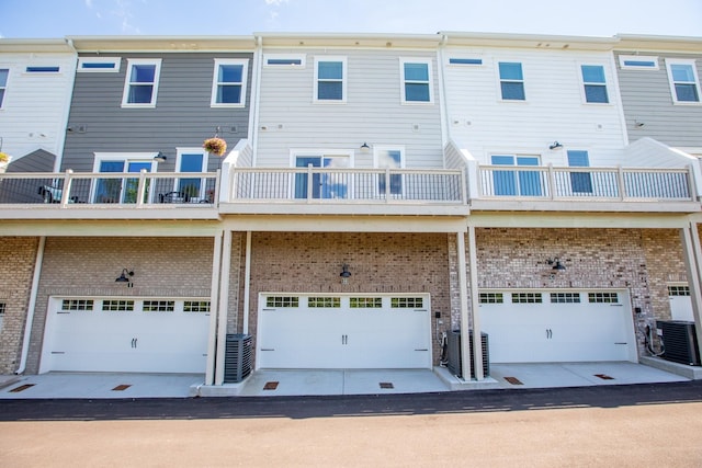 rear view of house featuring central air condition unit, an attached garage, and brick siding