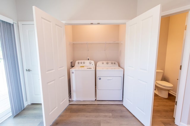 clothes washing area with laundry area, washer and clothes dryer, and light wood finished floors