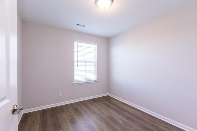 empty room featuring baseboards, visible vents, and dark wood-style flooring