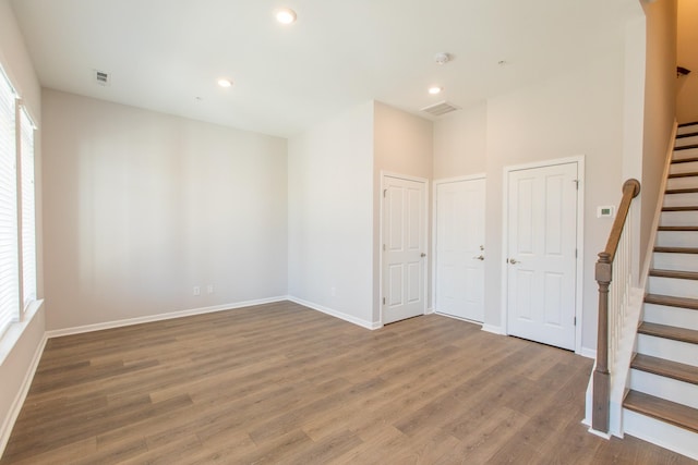 spare room with a wealth of natural light, visible vents, stairway, and wood finished floors