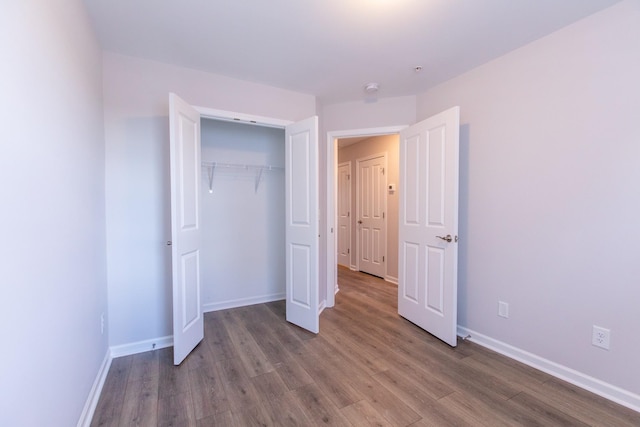 unfurnished bedroom with a closet, wood finished floors, and baseboards