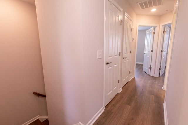 hall featuring baseboards, visible vents, and wood finished floors