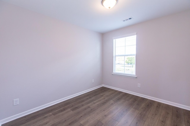 unfurnished room with dark wood finished floors, visible vents, and baseboards