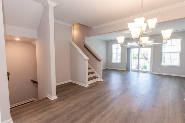 spare room featuring a notable chandelier, crown molding, baseboards, and wood finished floors