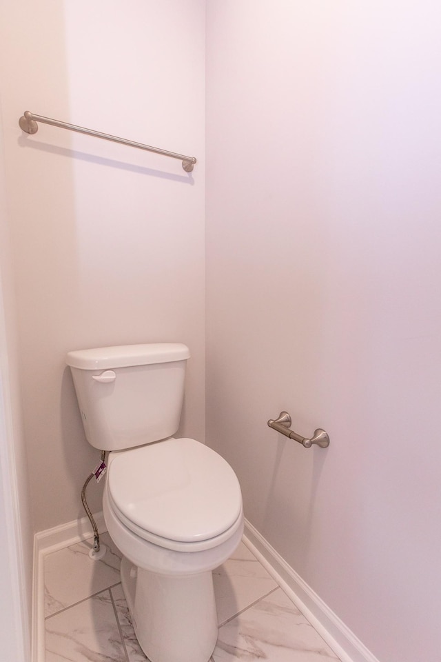 bathroom with marble finish floor, toilet, and baseboards