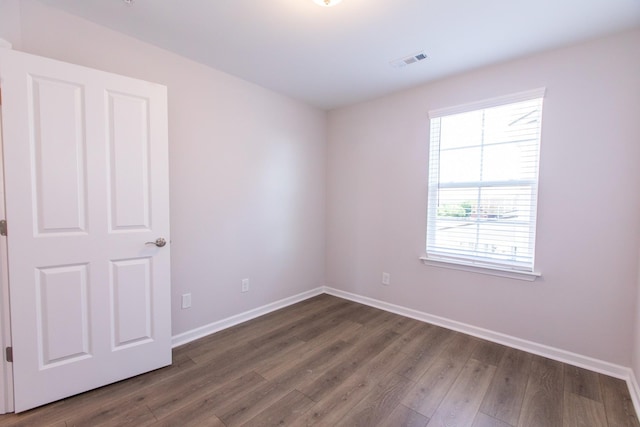 unfurnished room featuring visible vents, baseboards, and wood finished floors