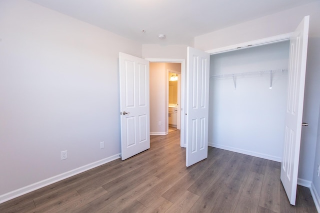 unfurnished bedroom featuring a closet, baseboards, and wood finished floors