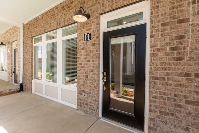 view of exterior entry with brick siding and a porch